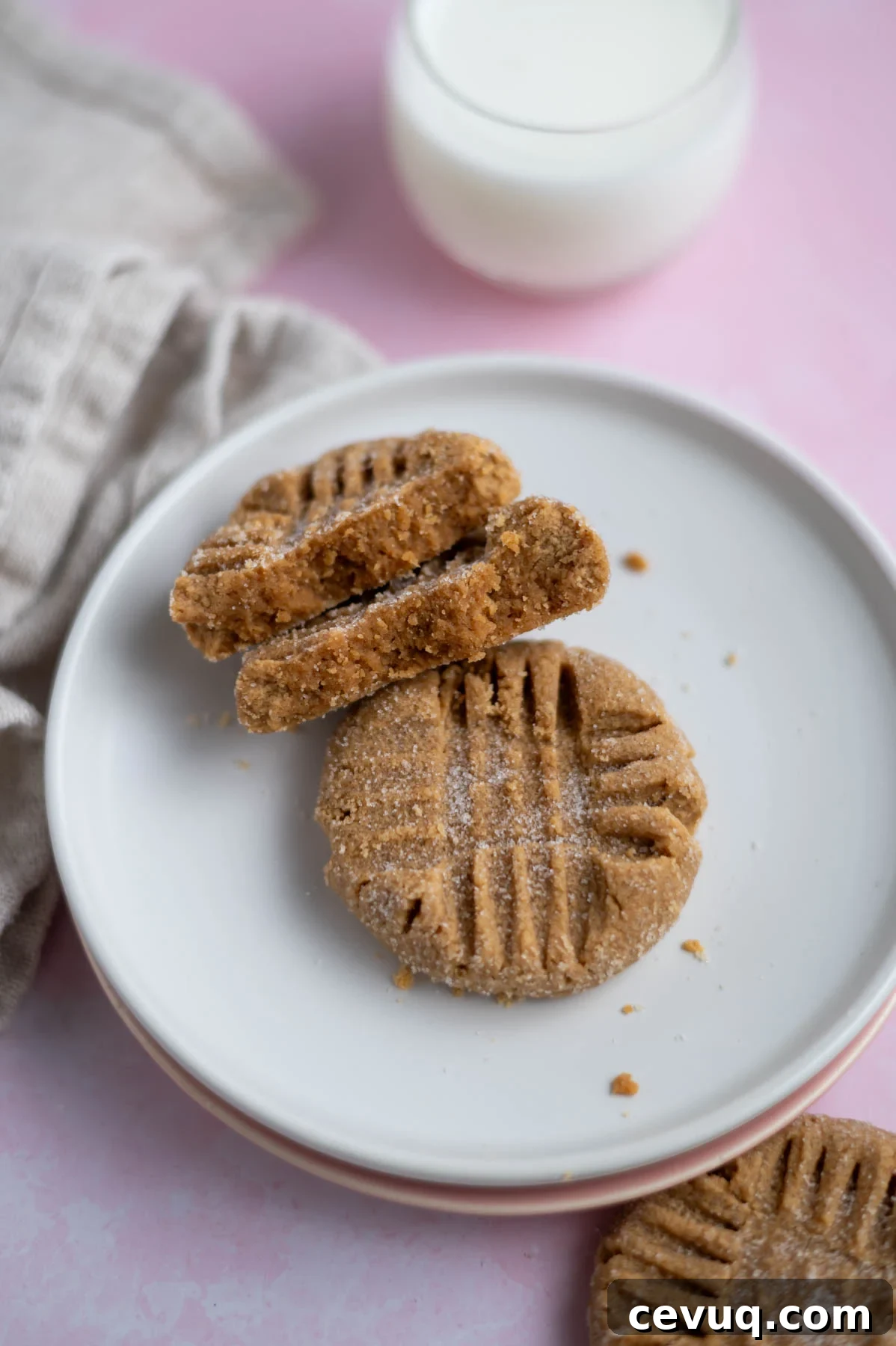 two small batch peanut butter cookies on a plate, one broken in half