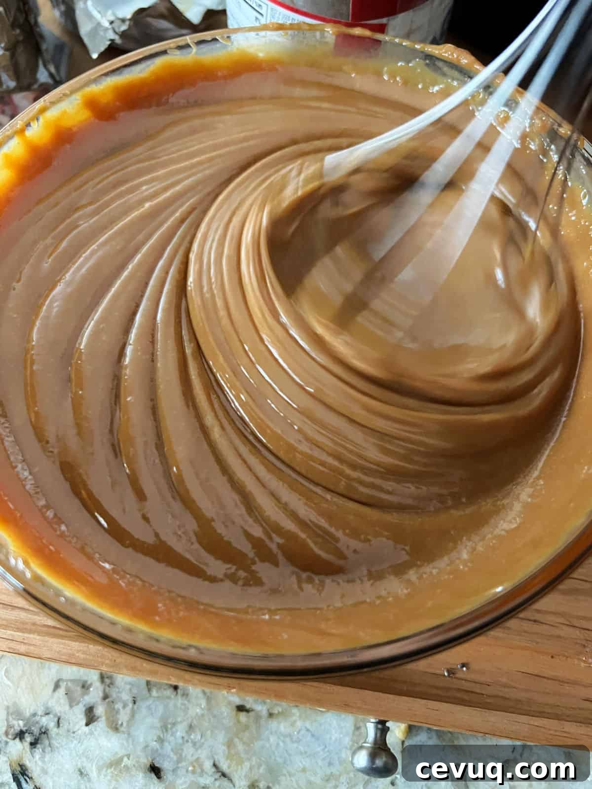caramel sauce in a bowl being stirred with a whisk.