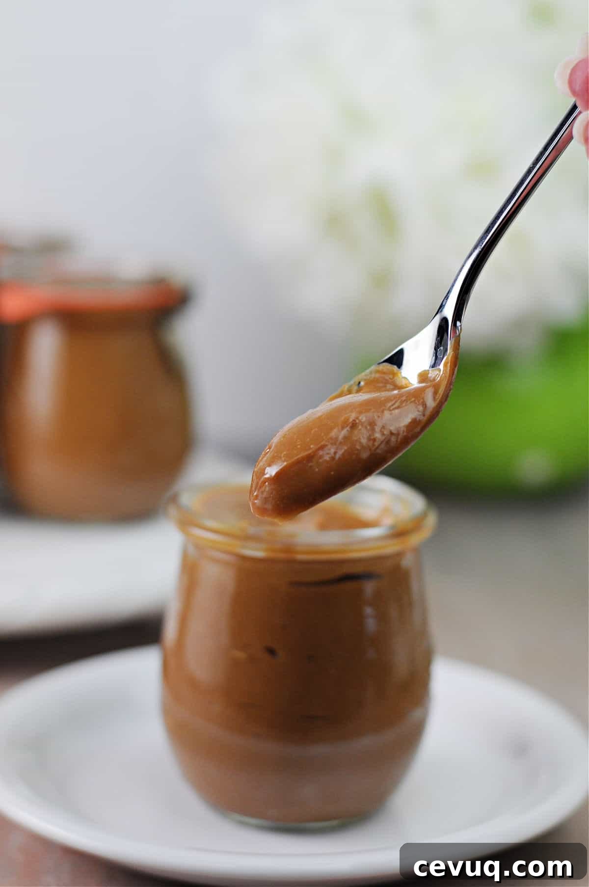 jar of instant pot caramel sauce with a spoon of sauce suspended above it.