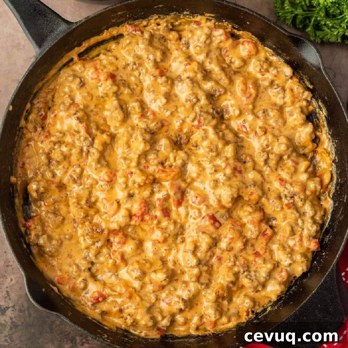 A skillet filled with cheesy chicken in a red pot.