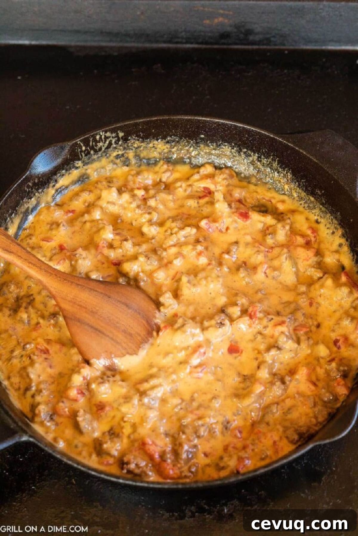 Melted cheese dip in a cast iron skillet with a wooden spoon
