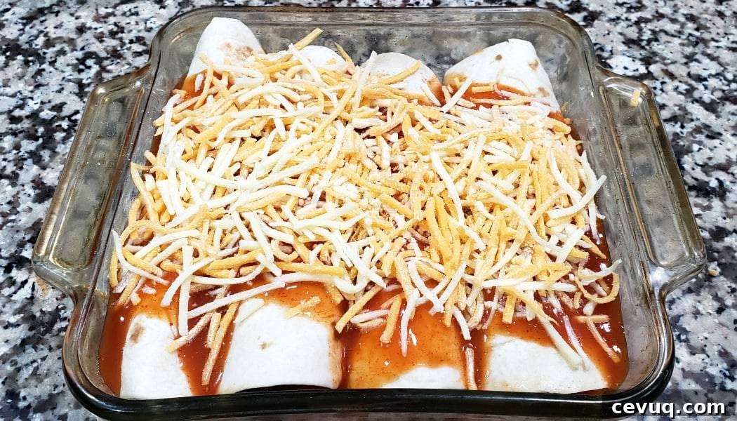4 chicken enchiladas topped with sauce and cheese in a baking dish