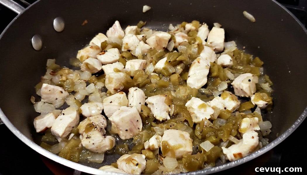chicken, onion, and green chiles cooking in a frying pan