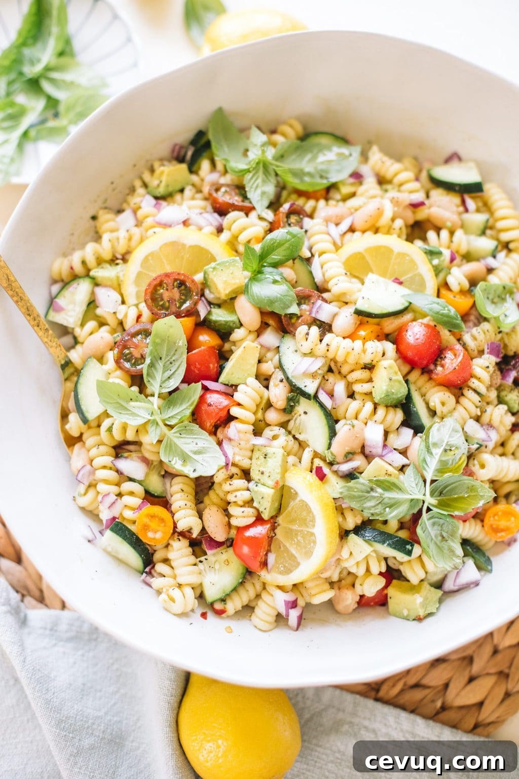 easy pasta salad with beans, avocado, cucumbers, tomatoes, basil in white bowl