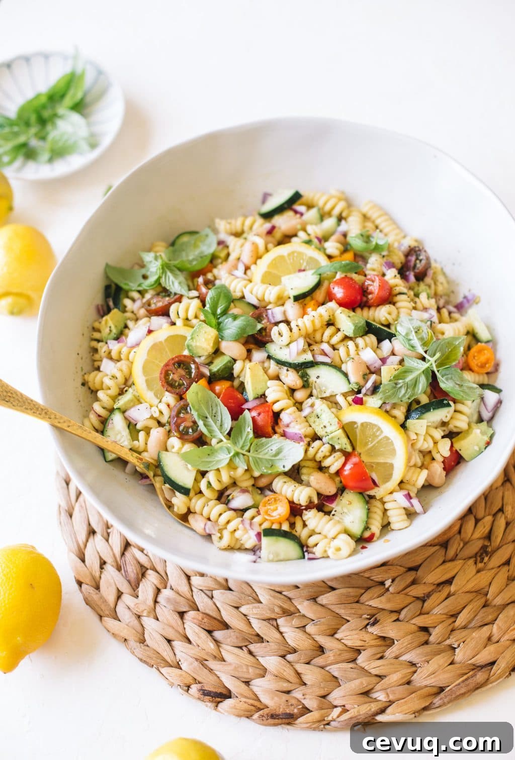 vegan pasta salad with cucumbers, tomatoes, basil in white bowl