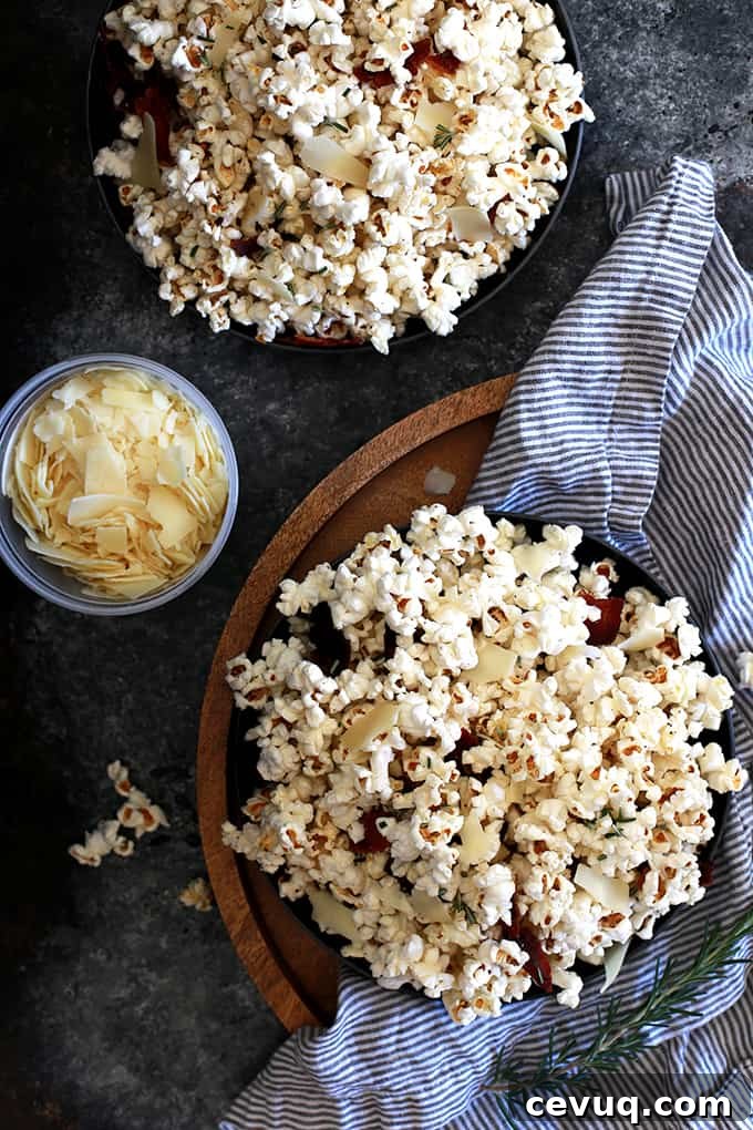 Close-up of popcorn tossed with rosemary, shaved Parmesan and bacon crumbles.