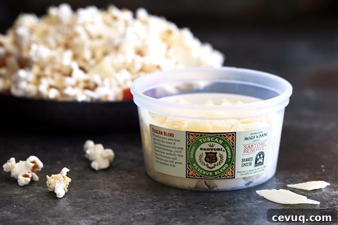 Hand sprinkling shaved Parmesan over warm bacon popcorn.