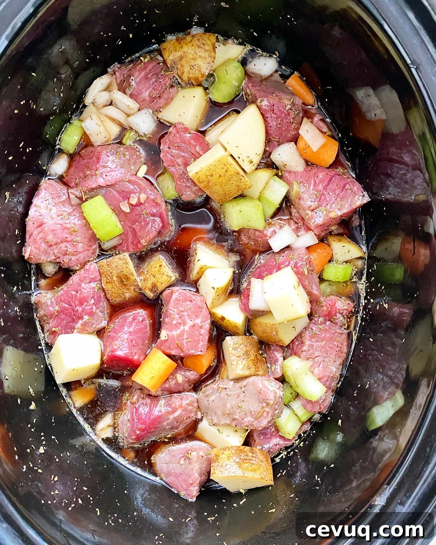 overhead shot of uncooked Guinness beef stew in a black slow cooker
