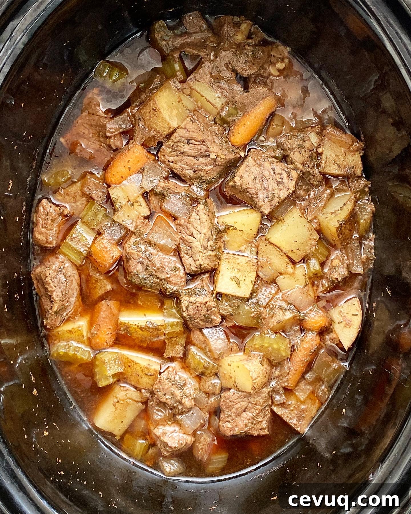 overhead shot of cooked Guinness beef stew in a black slow cooker