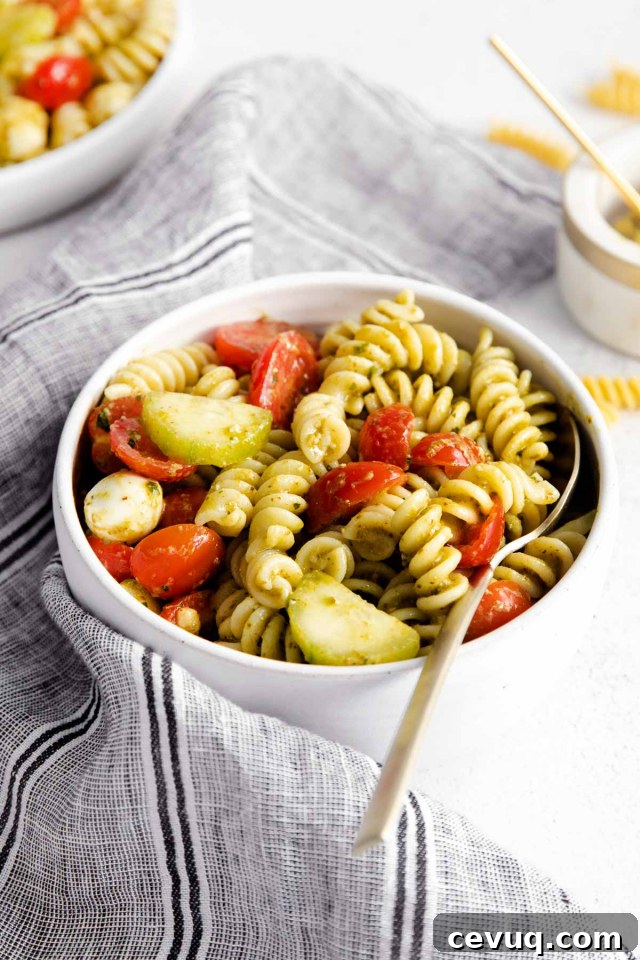 spoon in a bowl of summer pesto pasta salad