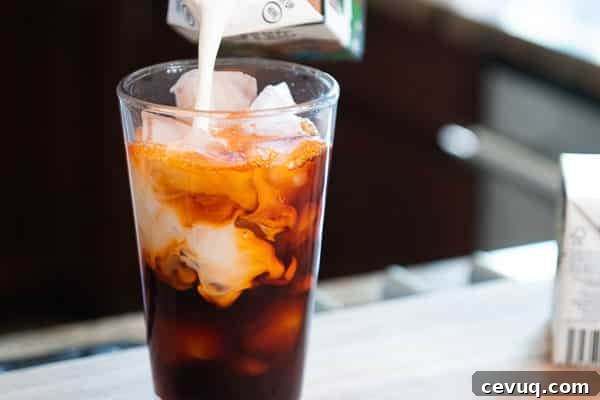 Pouring creamer into glass with iced Tea tea