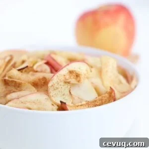 Crispy Air Fryer Apple Slices Recipe for Quick Snacks 4 Air fried apple slices in a white bowl with an apple in the background.
