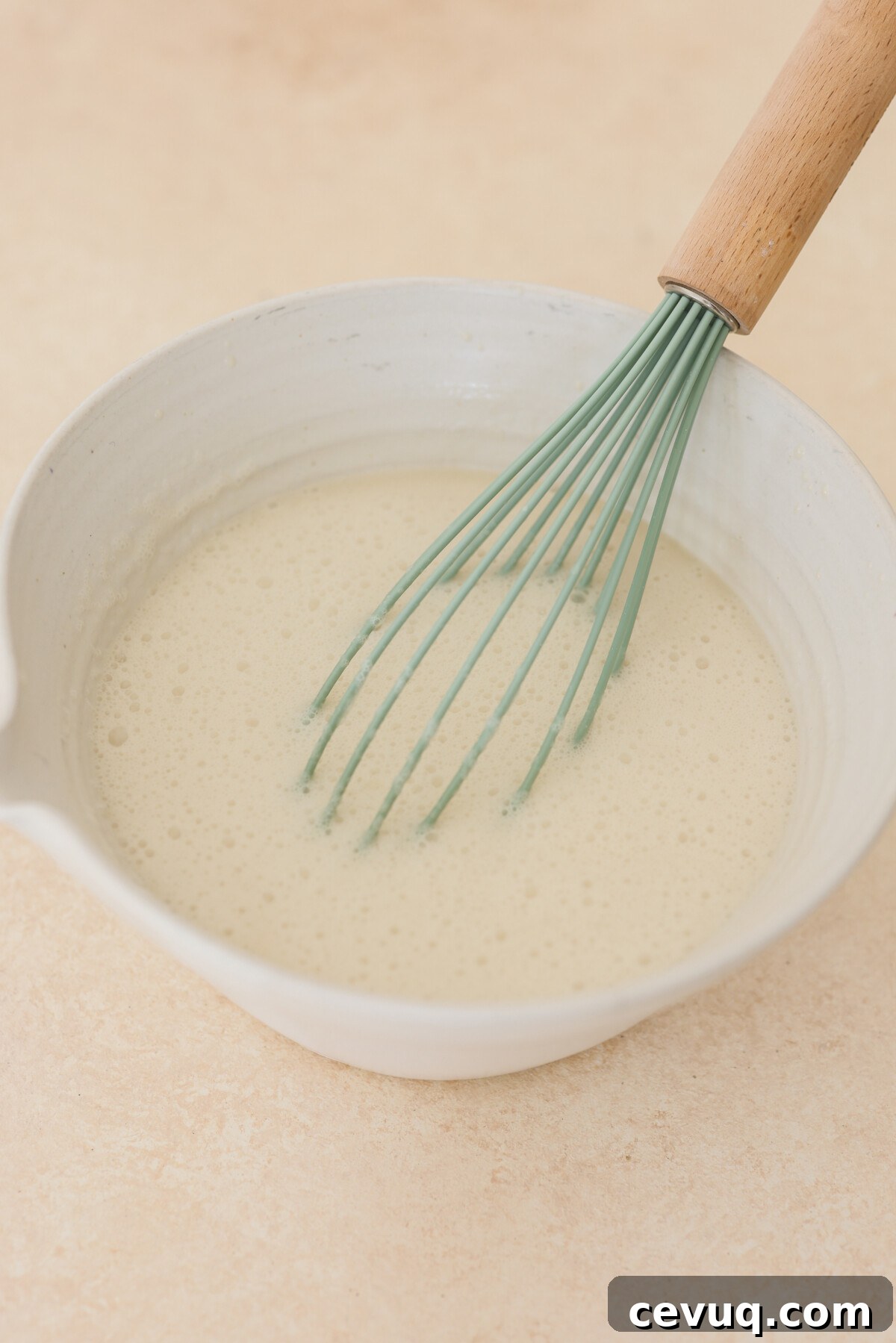 a whisk stirring milk in a bowl