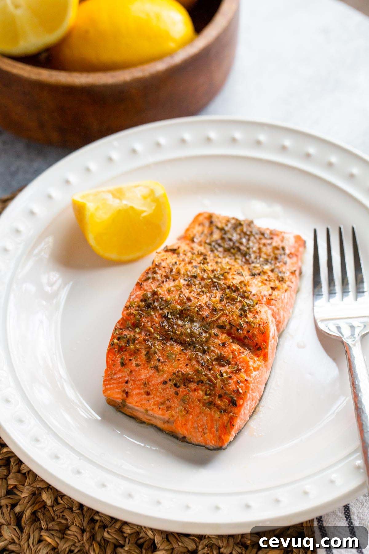 Cooked salmon on a plate with lemon wedge.