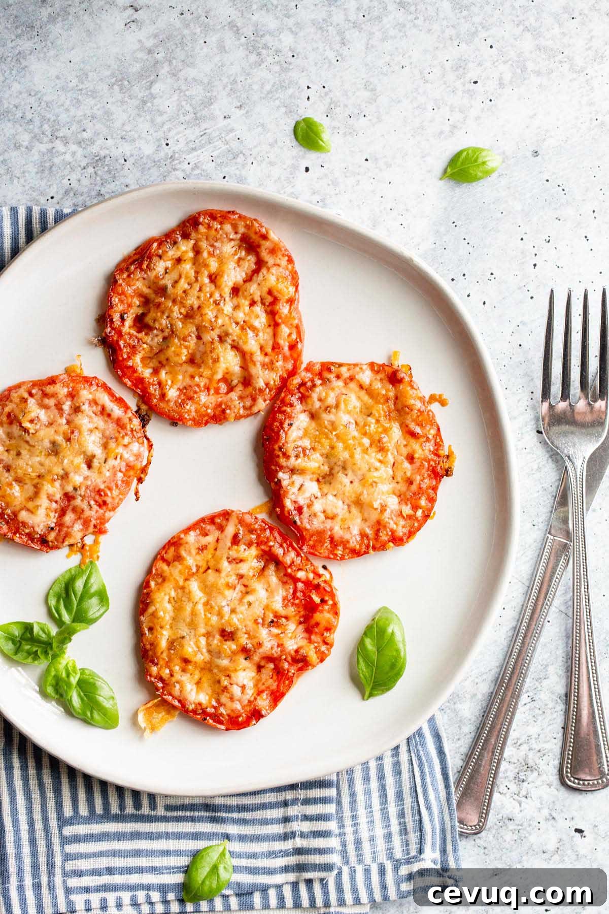 Roasted tomatoes with parmesan cheese on a white plate.