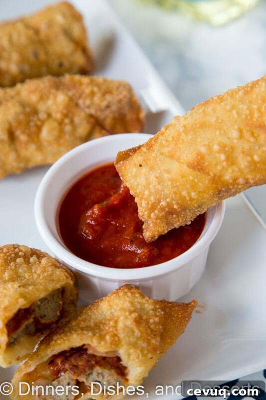 meatball sub egg rolls on a plate with dipping sauce
