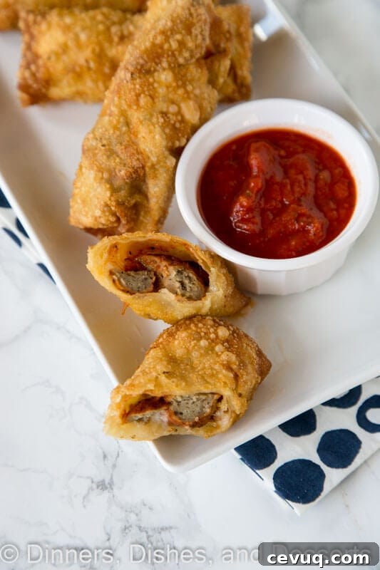 meatball sub egg rolls on a plate with dipping sauce