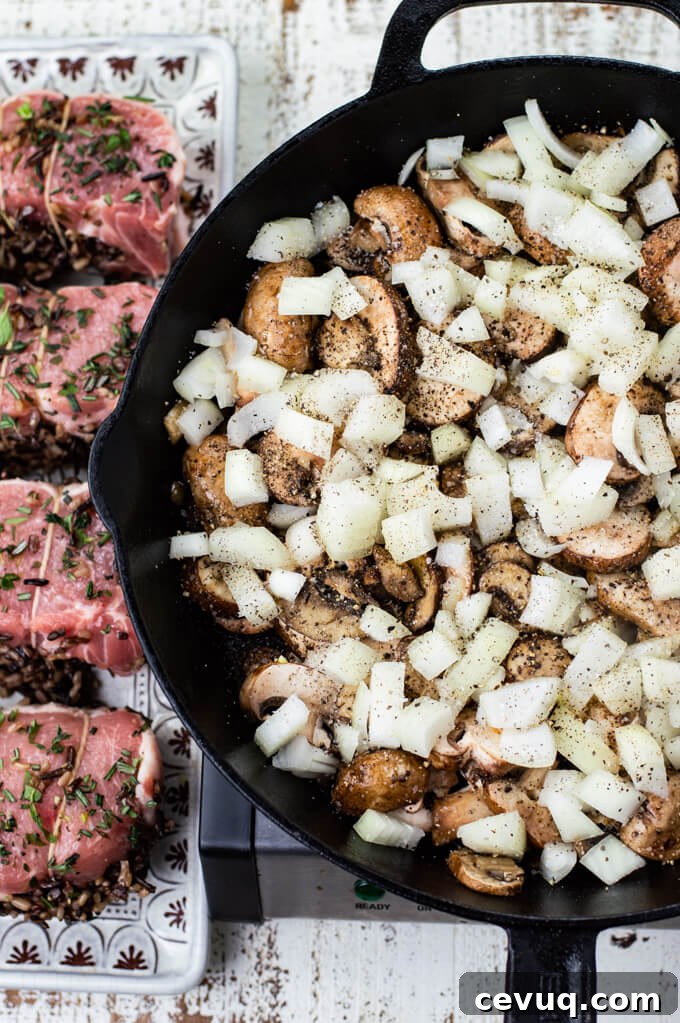 A pan of sautéed mushrooms with raw chopped onions on top. Four uncooked wild rice stuffed pork chops sit next to it. 