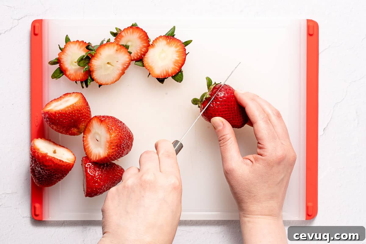 cutting tops off of strawberries on cutting board