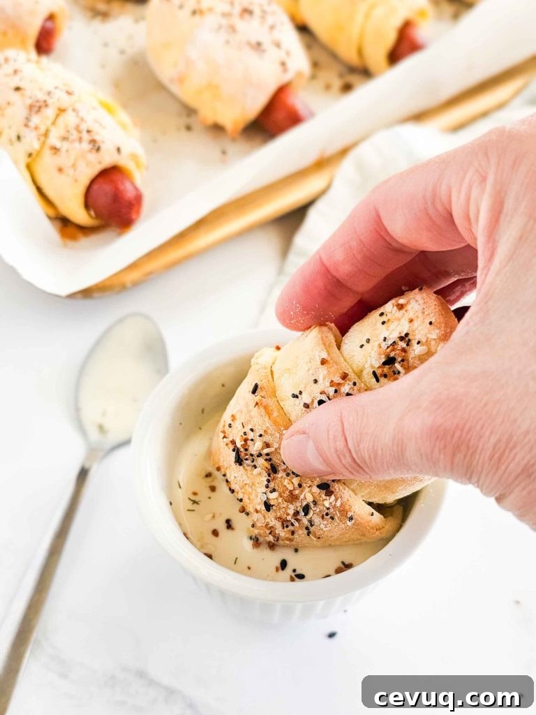 wrapped hot dog being dipped in sauce