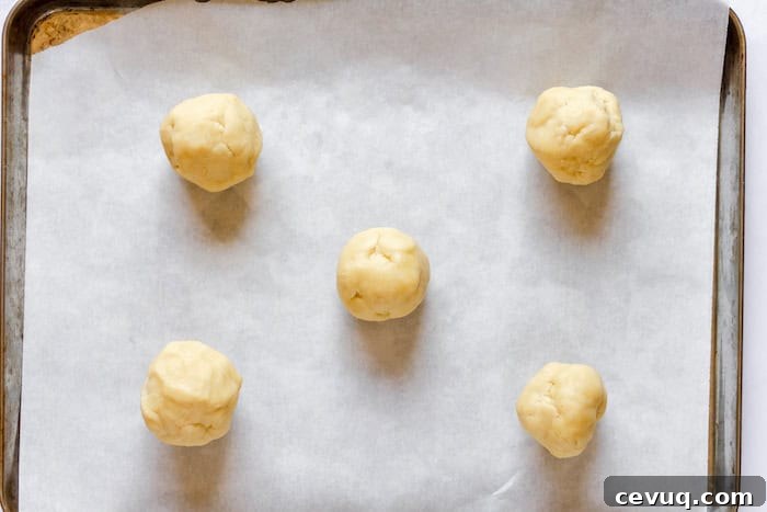 Image, taken from above, shows a cookie sheet with 5 cookie dough balls spaced on the pan. 