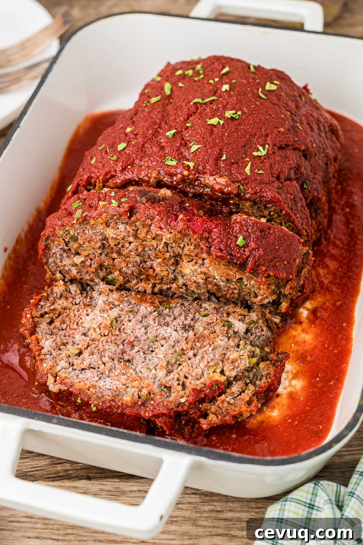 Side view of a sliced Cajun meatloaf with a tomato sauce.