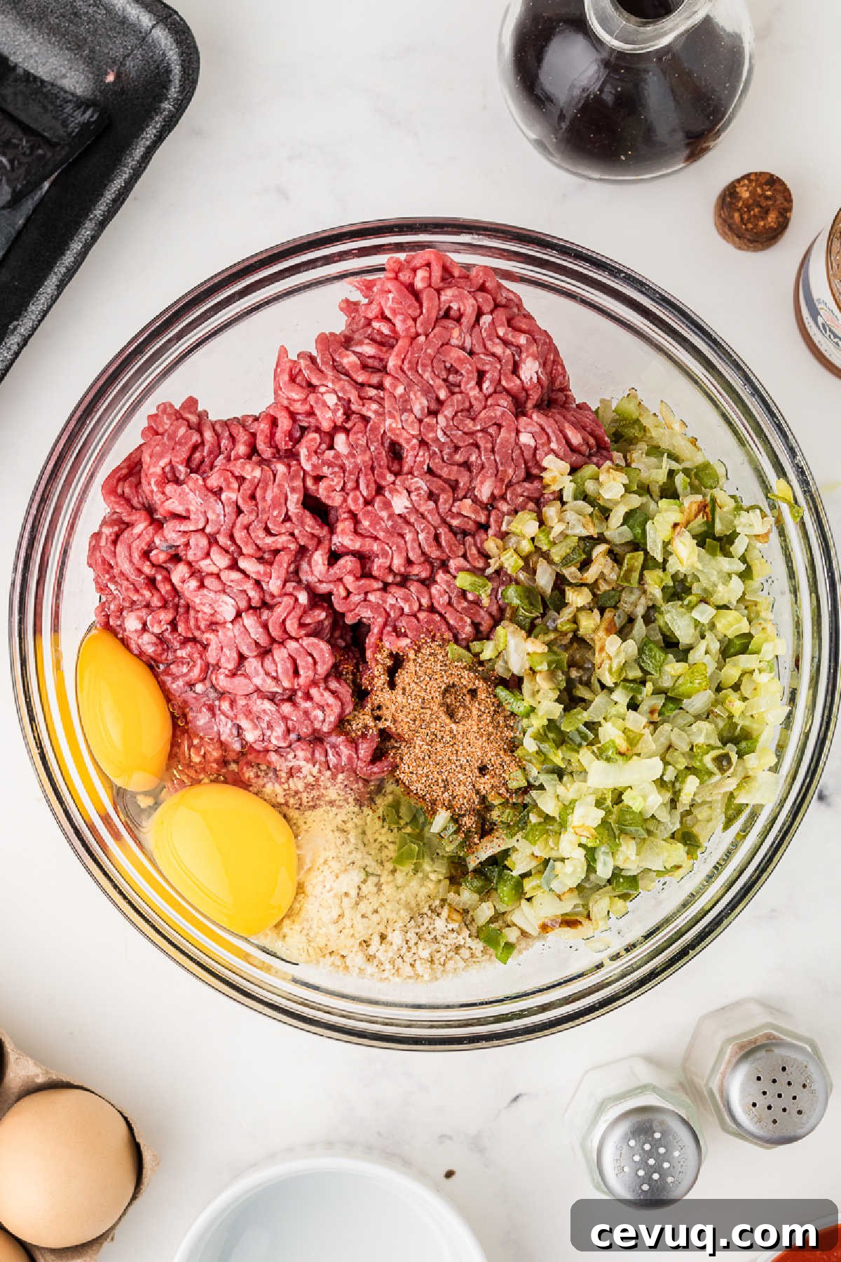 A large mixing bowl with ground beef, vegetables, breadcrumbs and eggs.
