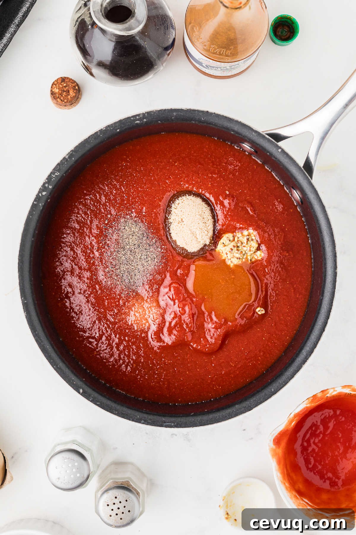 A sauce pan with tomato sauce and seasonings.