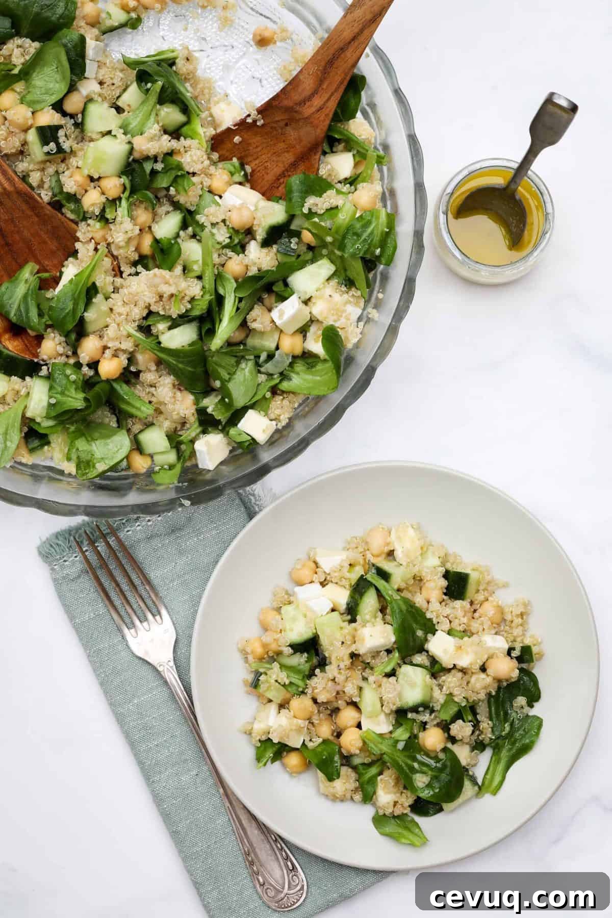 Plate of quinoa chickpea salad next to big bowl of salad and vinaigrette