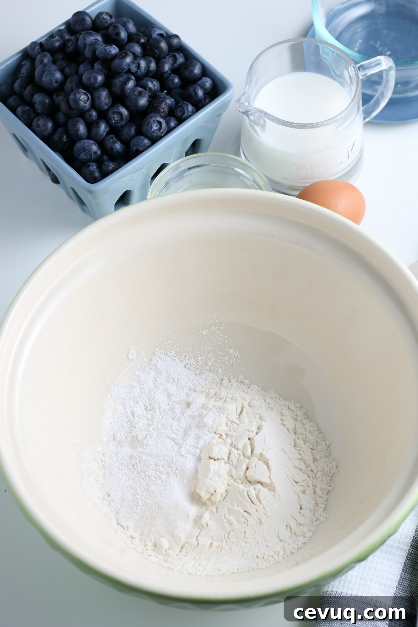white glass bowl filled with dry ingredients for blueberry pancakes.