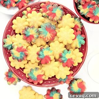 Classic Spritz Cookie Recipe Using Shortening for Crispy Shapes 7 Spritz cookies, some plain and some colored, on a red plate.