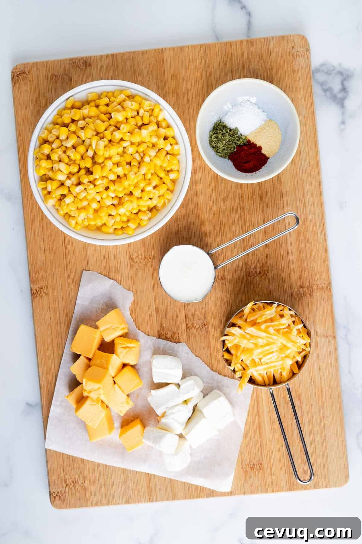 Cheesy Velveeta corn casserole ingredients: corn, cubed Velveeta, cubed cream cheese, heavy cream, garlic powder, dried parsley, kosher salt, and smoked paprika.