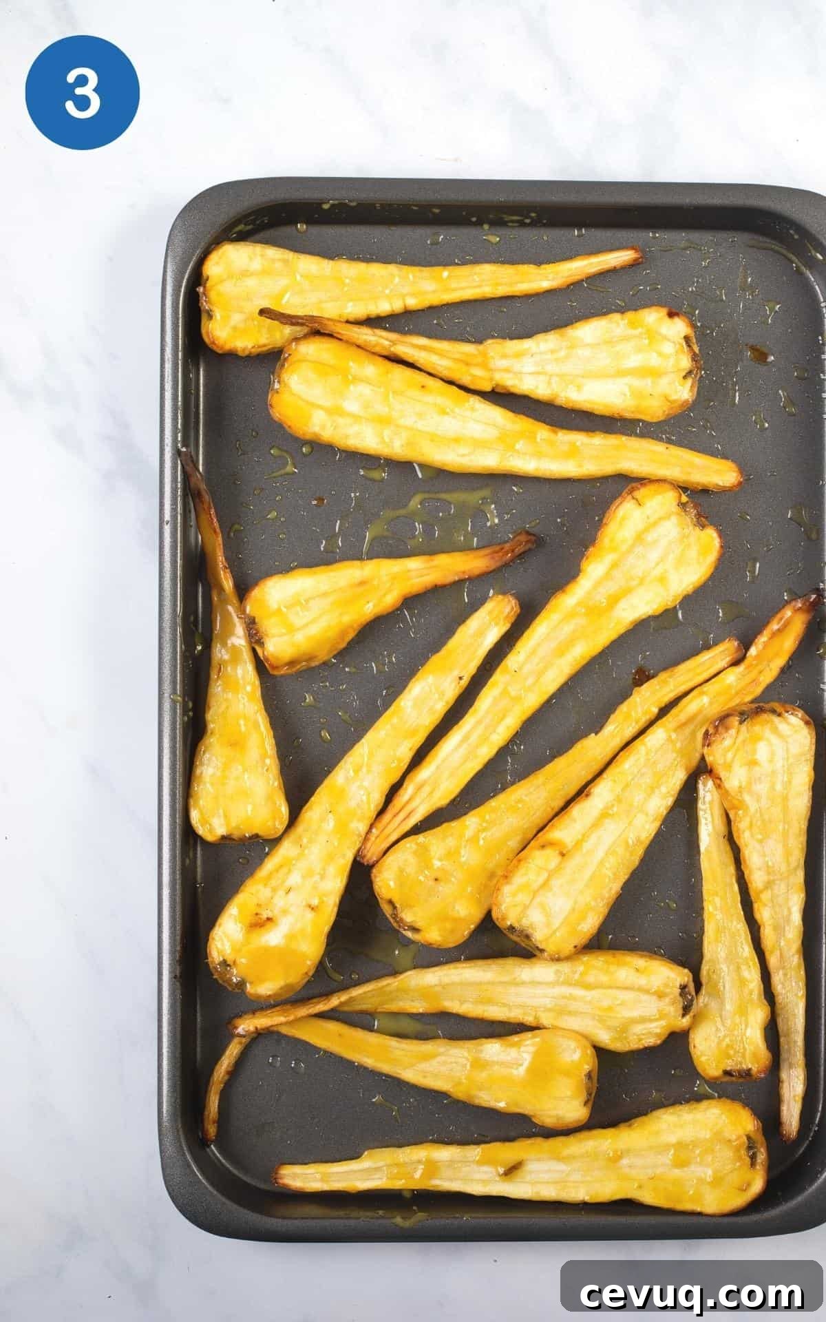 Crispy Roasted Parsnips with Honey and Thyme 6 overhead view of these roasted parsnips on a grey baking tray ready to roast.