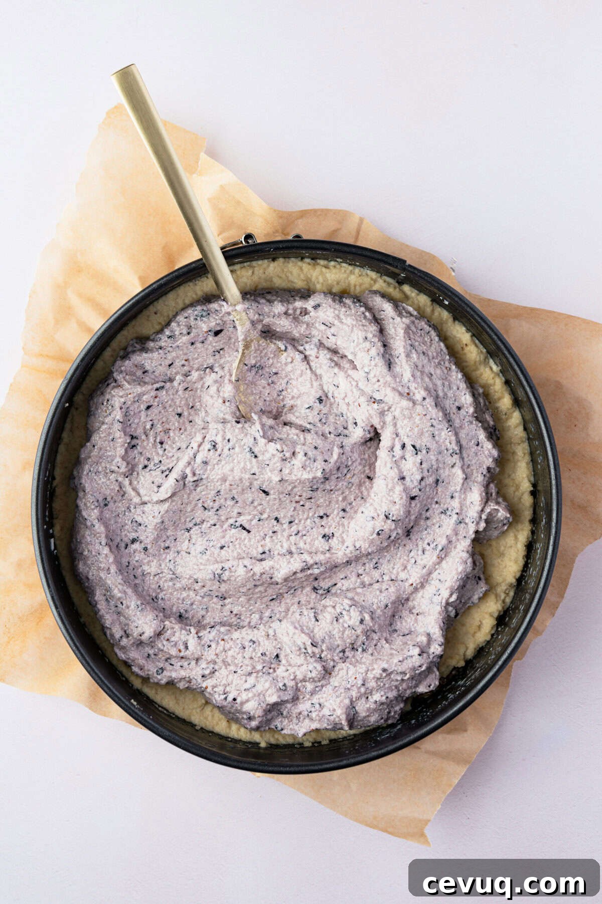 A springform pan filled with a thick and creamy blue spread with a spoon in it.