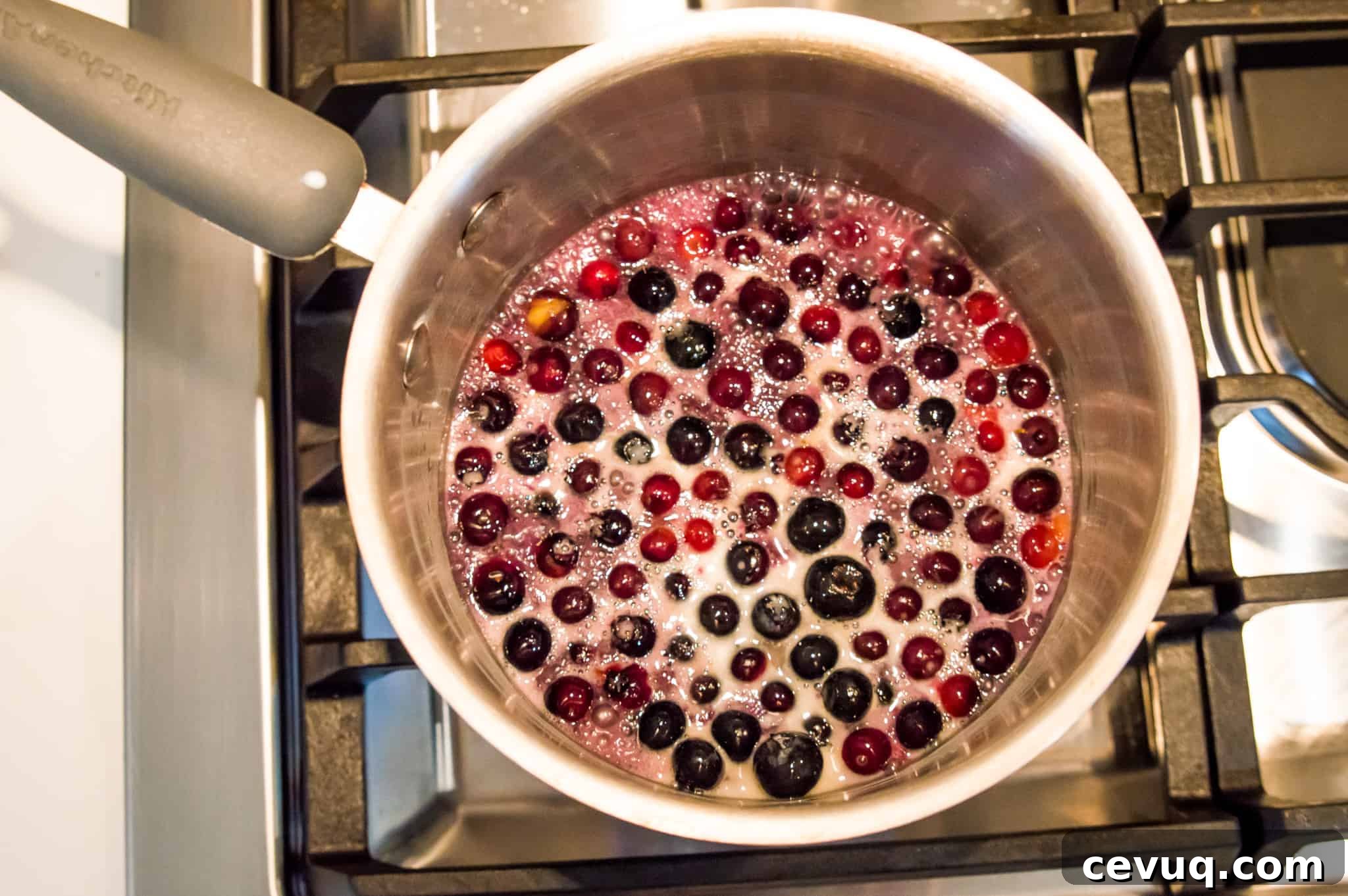 Blueberries and coconut milk simmering in a pot on the stovetop.
