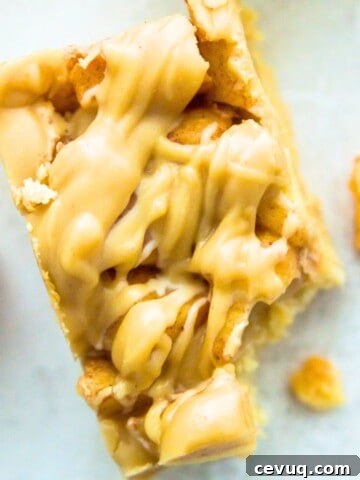 A paleo apple pie bar with a bite out of it and pieces of cooked apples beside it.