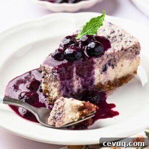 A piece of vegan blueberry cheesecake topped with blueberry sauce and blueberries.