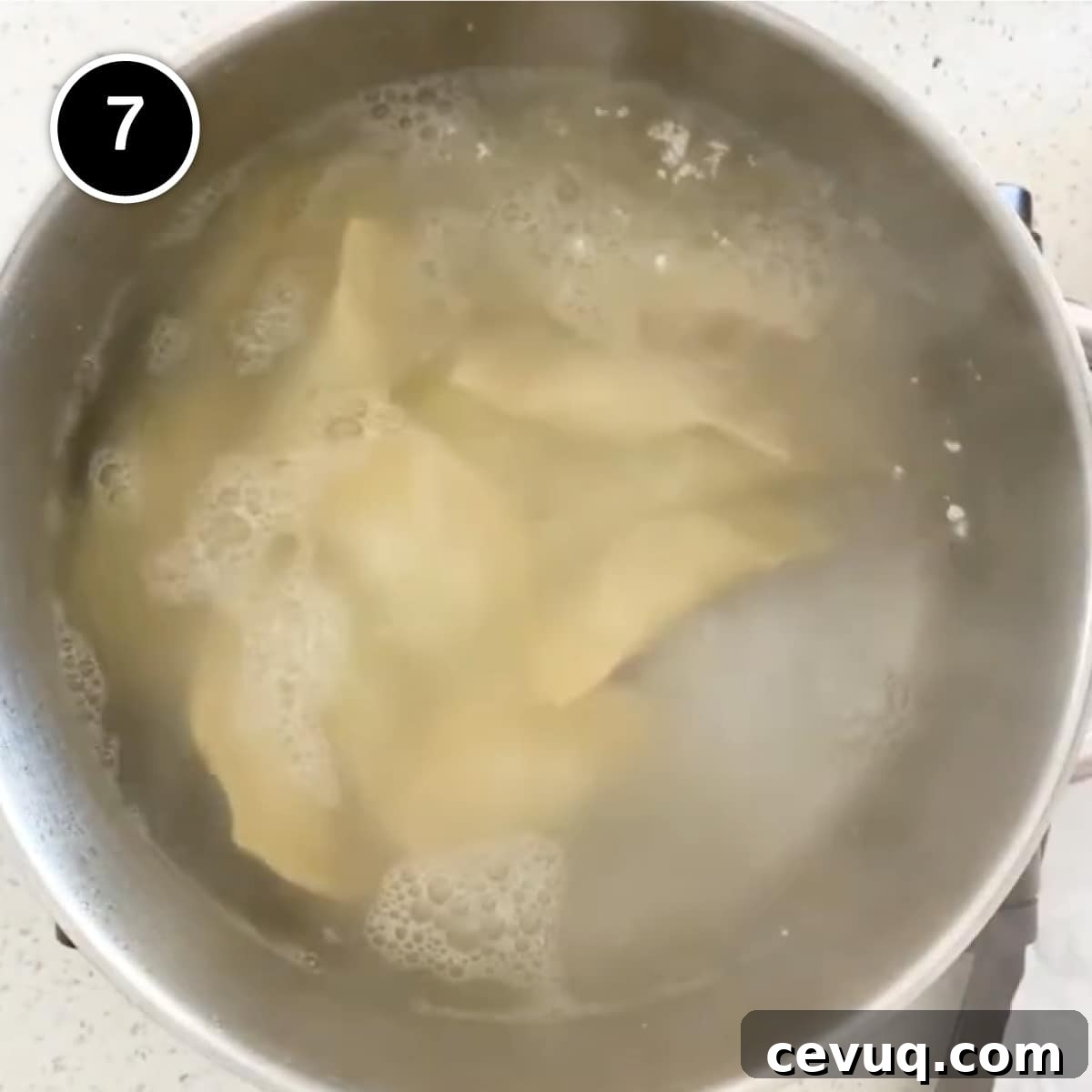 Mezzelune pasta cooking in a pan of water.