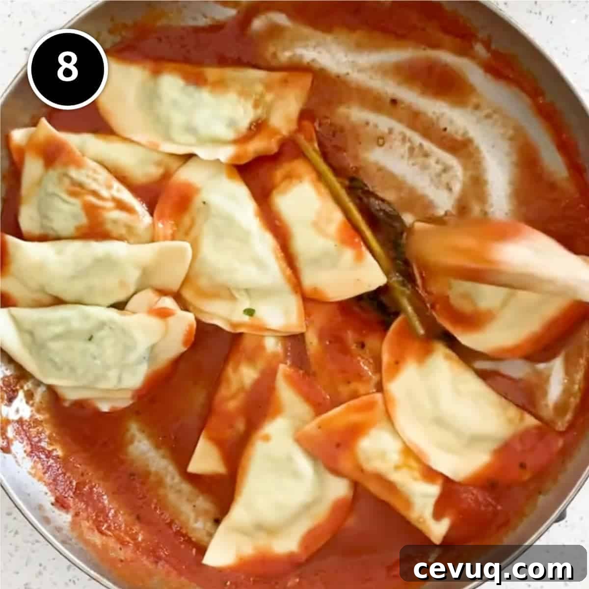 Freshly cooked mezzelune pasta in a frying pan of tomato sauce