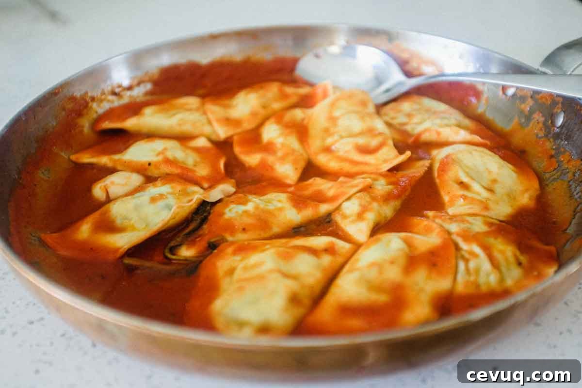 A plate of mezzelune pasta half moons with tomato sauce and sprinkling of fresh parmesan cheese