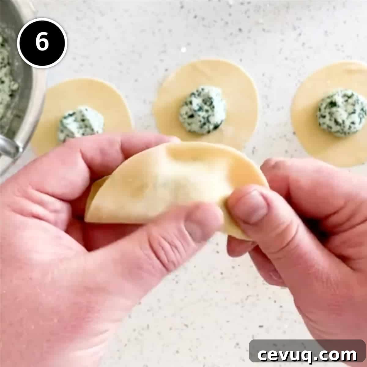Folding a disc of pasta into a half moon shape.