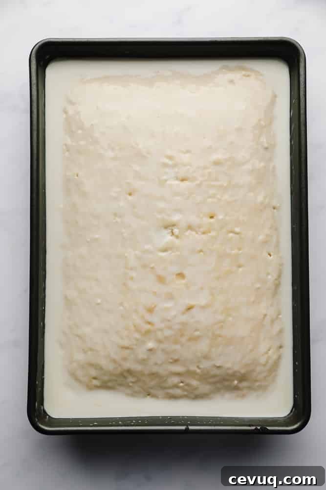 milk poured over a vanilla cake in a pan