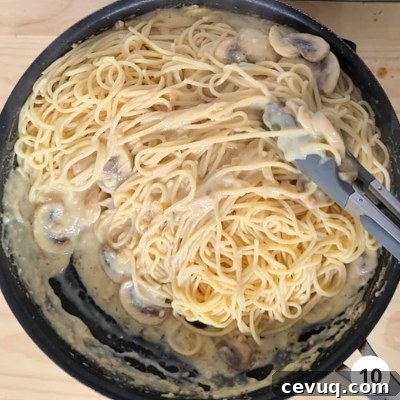 Creamy Mushroom Pasta Without Cream — Dairy-Free Recipe 13 Pasta being tossed and mixed into creamy mushroom sauce with a pair of tongs