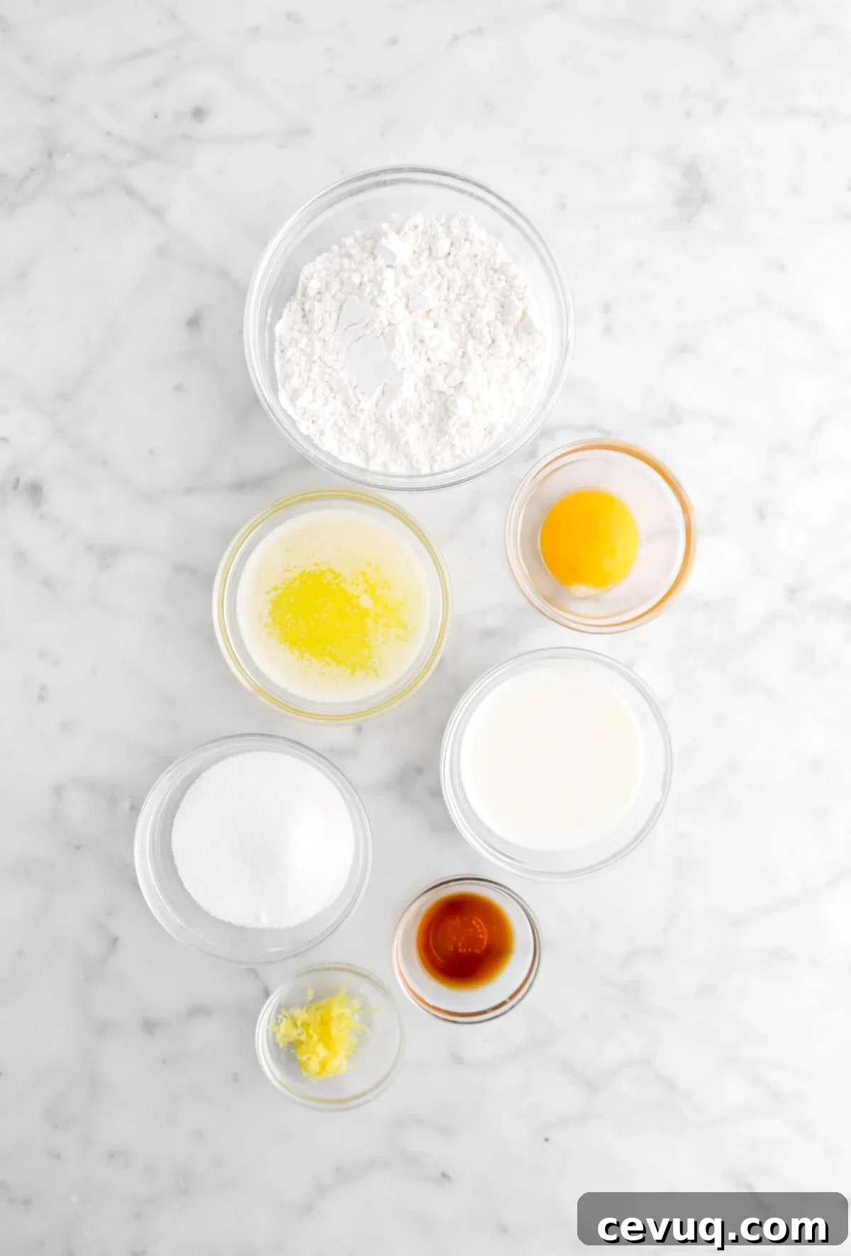 cake flour, egg yolk, melted butter, milk, vanilla, lemon zest, and sugar on marble surface