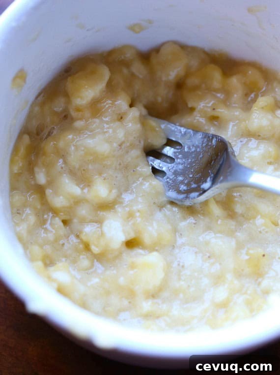 Close up of mashed bananas in a bowl with a fork.