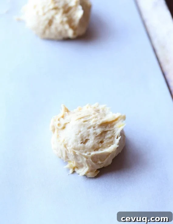 Drops of banana cookie dough on a lined baking sheet.