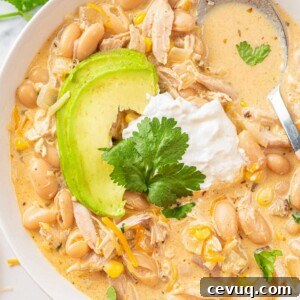 white chicken chili recipe on a white plate, topped with sour cream and avocado