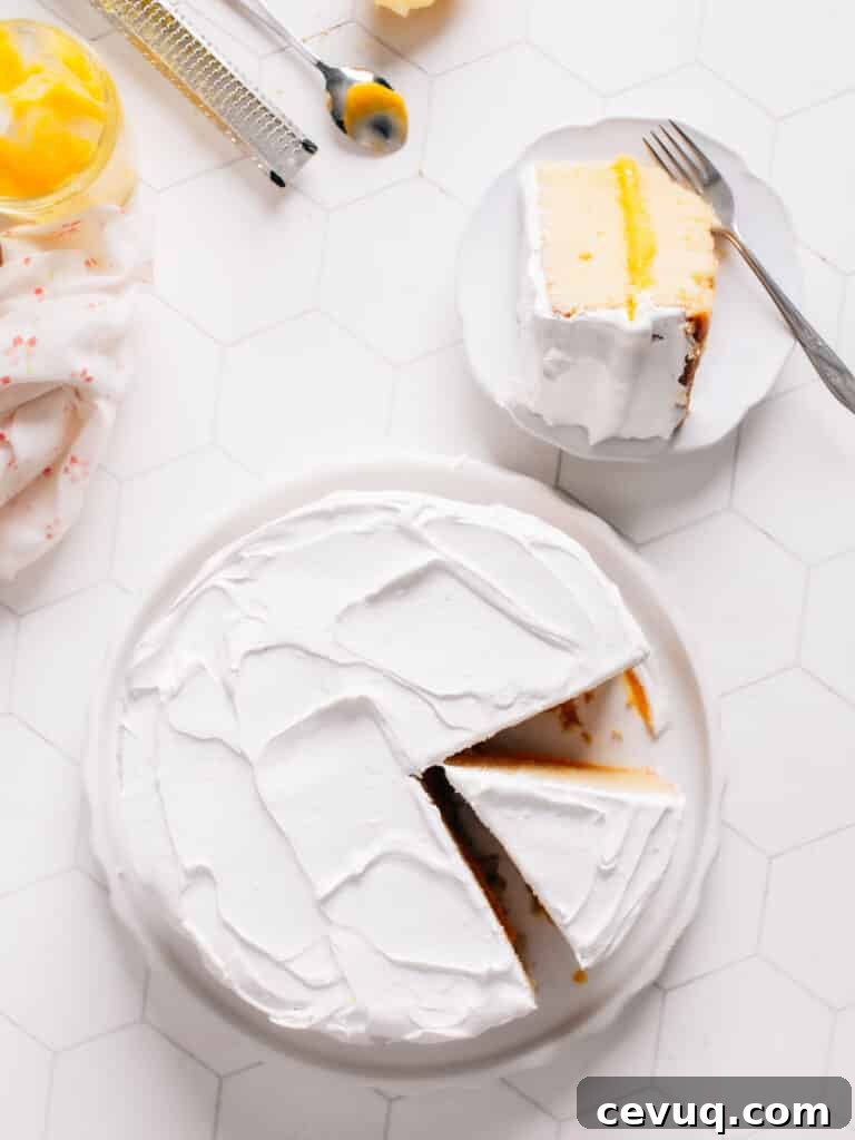 A scrumptious lemon curd cake has been sliced and plated on a white dish with a fork by side.