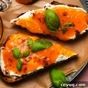 Toasted bread topped with ricotta and mango apricot jam, garnished with basil leaves.