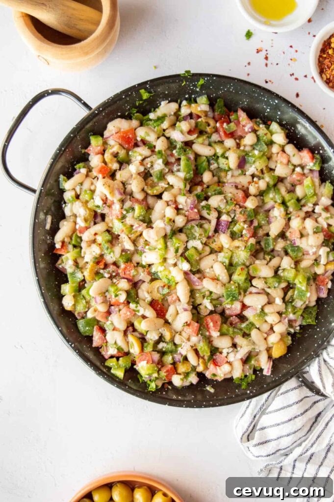 A black pan with white bean salad on a white background.